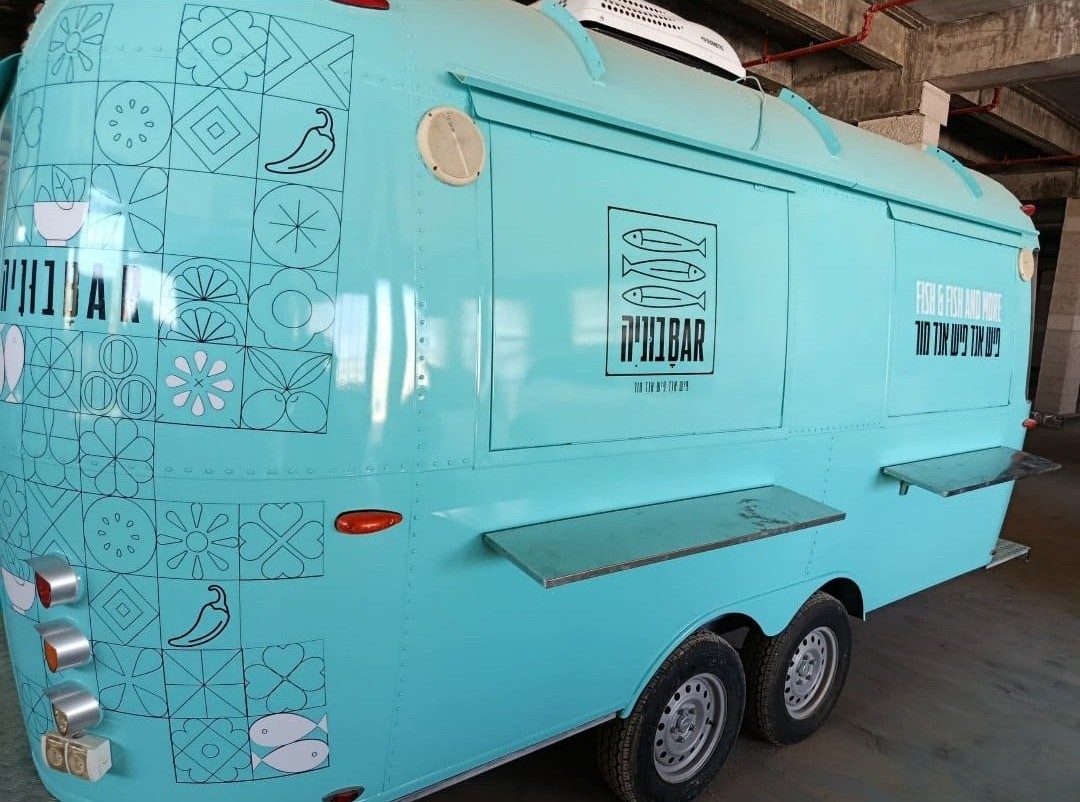 The turquoise street food trailer with illustrated graphics along its side.